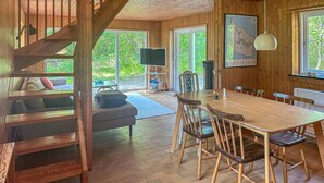 L’intérieur d’un chalet en bois comprend un coin repas, un canapé et un escalier.