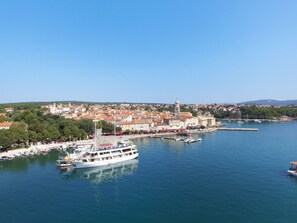 A coastal town with a prominent white boat docked at the pier, surrounded by buildings and greenery.