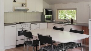 Una cocina moderna con armarios blancos, estufa a gas, microondas y una ventana que proporciona luz natural.