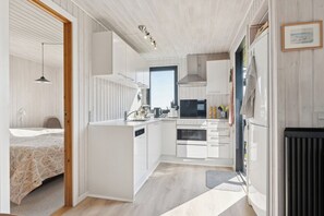 A modern kitchen with white cabinetry, a built-in oven, and a large window.