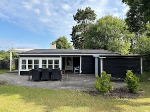 Une maison moderne dotée d’un patio couvert, d’un coin repas et d’un garage.