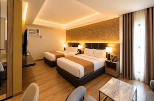 Habitación de hotel con dos camas, un escritorio, una silla, una mesa y un televisor.