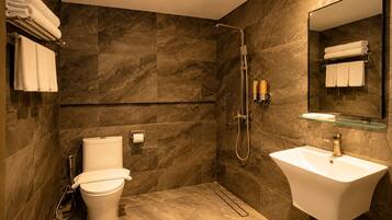 A modern bathroom with a toilet, a glass shelf, a sink, and a shower.