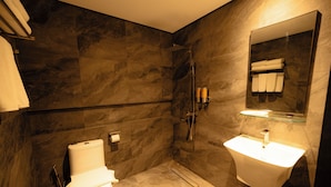 Ein modernes Badezimmer mit Toilette, Dusche und Waschbecken, alles vor einer Wand aus dunklem Marmor.