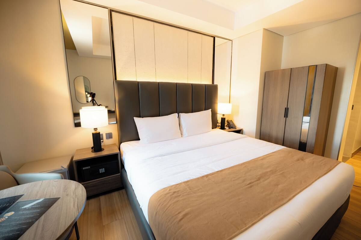 Ett hotellrum med en stor säng, sängbord, en garderob och en spegel.