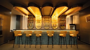 Eine Bar mit mehreren Hockern, Flaschenregalen und einer Theke.