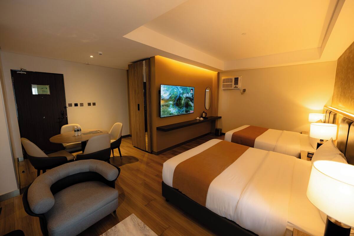 Ett hotellrum med två sängar, en TV, ett skrivbord och en stol.