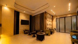 Eine großzügige Lobby mit modernem Design, ausgestattet mit einer Sitzecke, Sofas und Sesseln, einem an der Wand montierten Flachbildfernseher und einer großen Schiebetür.