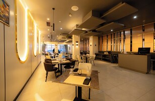 A modern restaurant with tables, chairs, and a bar area.
