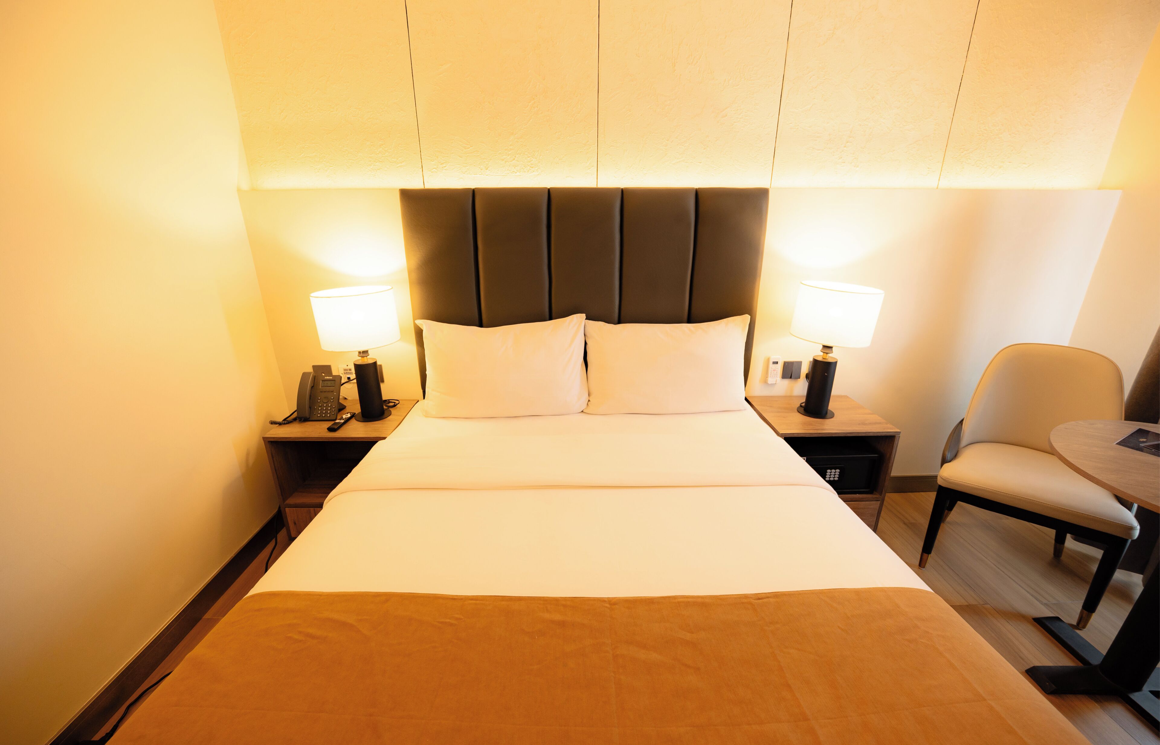 A hotel room with a large bed, two bedside tables with lamps, a chair, and a small table.