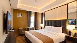 Une chambre d’hôtel avec un grand lit, un bureau, une chaise, une télévision et un miroir.