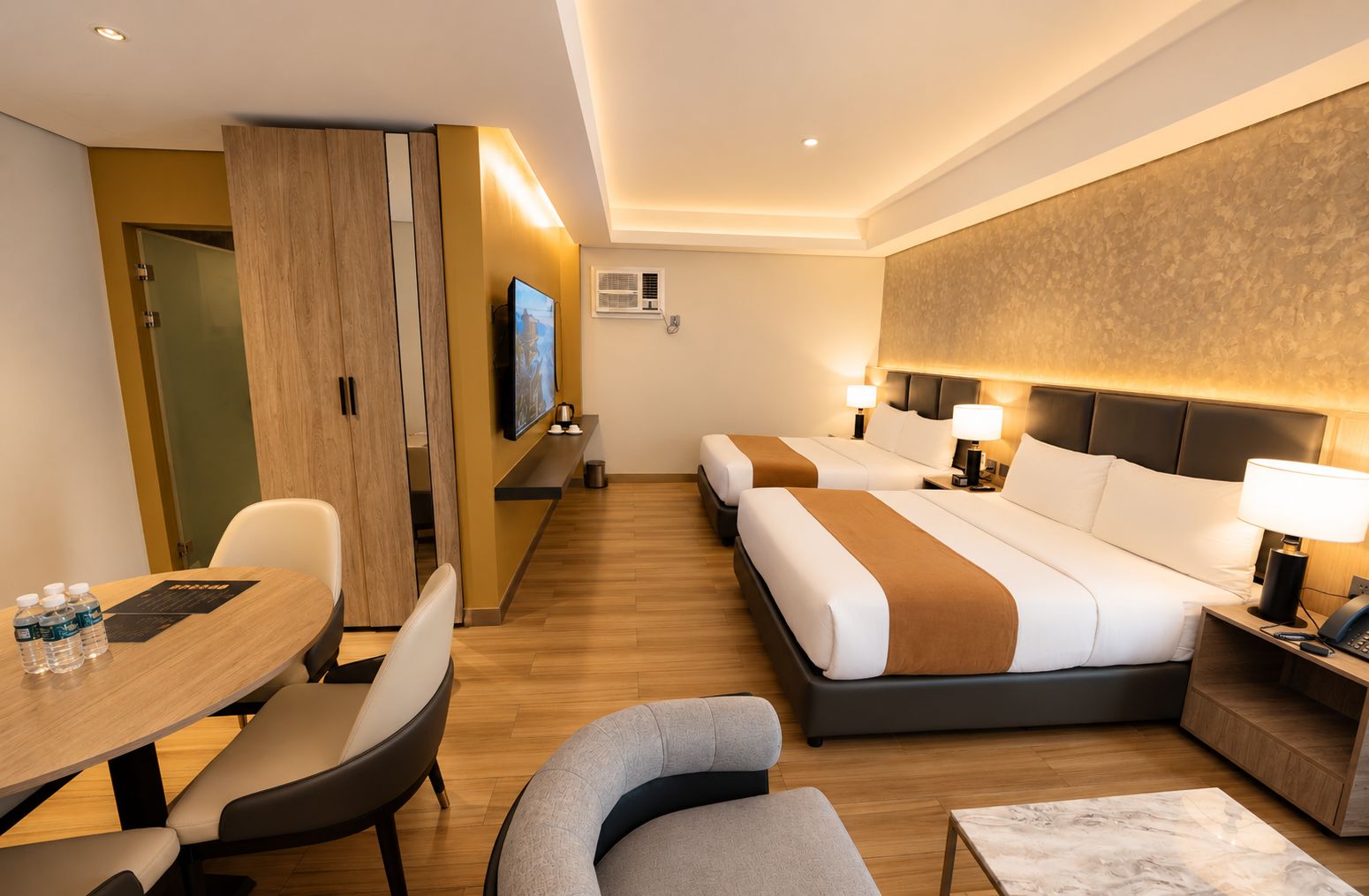 Habitación de hotel con dos camas, un escritorio, sillas, un televisor y un minibar.