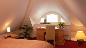 A bedroom with a bed, a desk, a chair, a lamp, a potted plant, and a window. - Küstenwaldvilla in Dierhagen (Dierhagen)