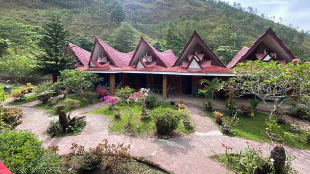 A row of triangular-roofed buildings with a garden in front. - Roman Sinasi Hotel (Merek)