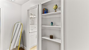 A hallway with a white door, a mirror, and a shelf with a globe, books, and a vase.