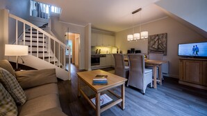 A modern living room with a staircase, a dining area, and a kitchen.