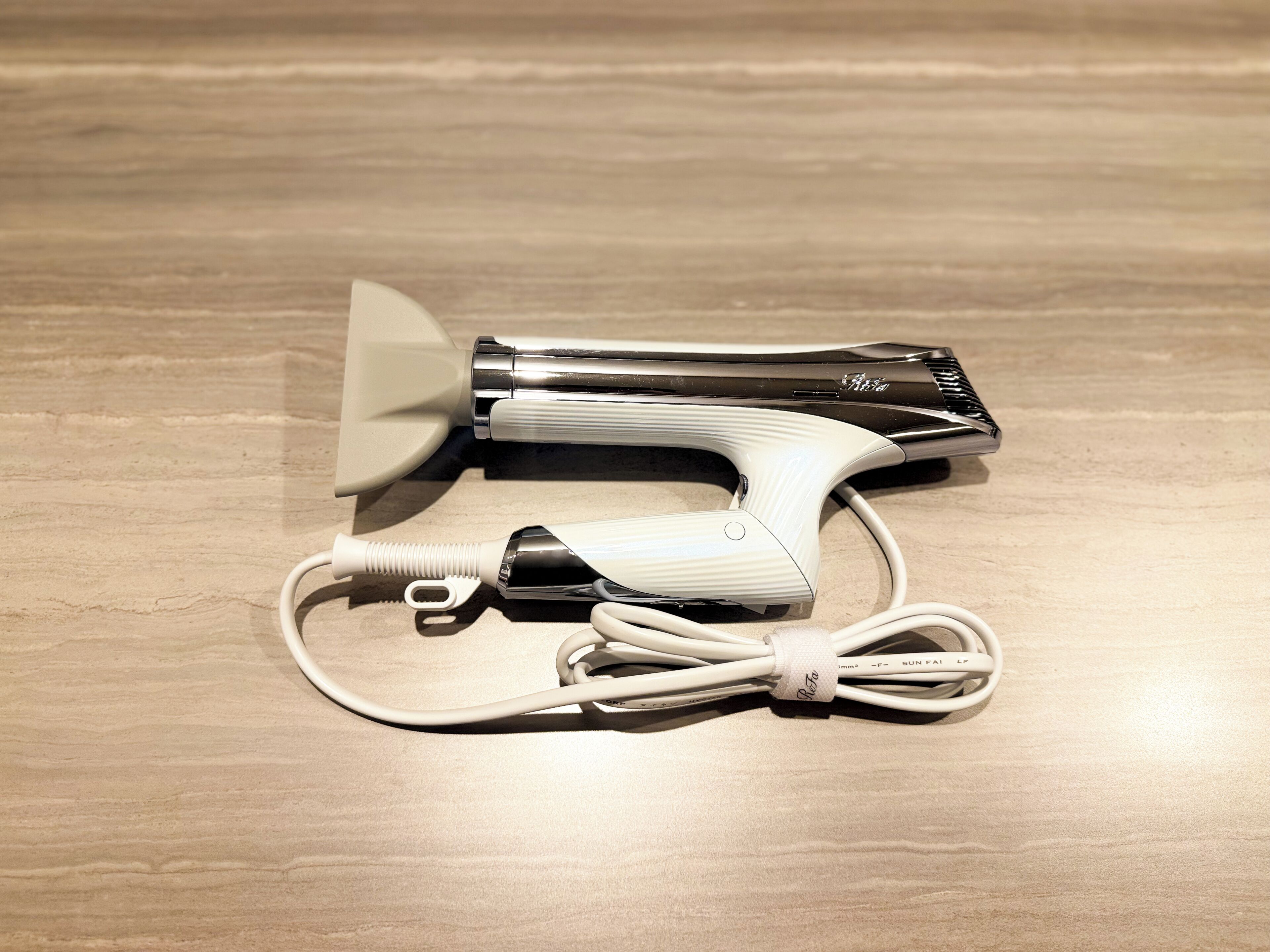 A hair straightener and its charging cable on a wooden surface.