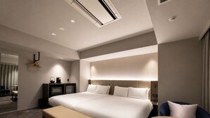 A modern hotel room with a large bed, a bedside table, a bench, and a small table. - Randor Hotel Sapporo Prestige (Sapporo)