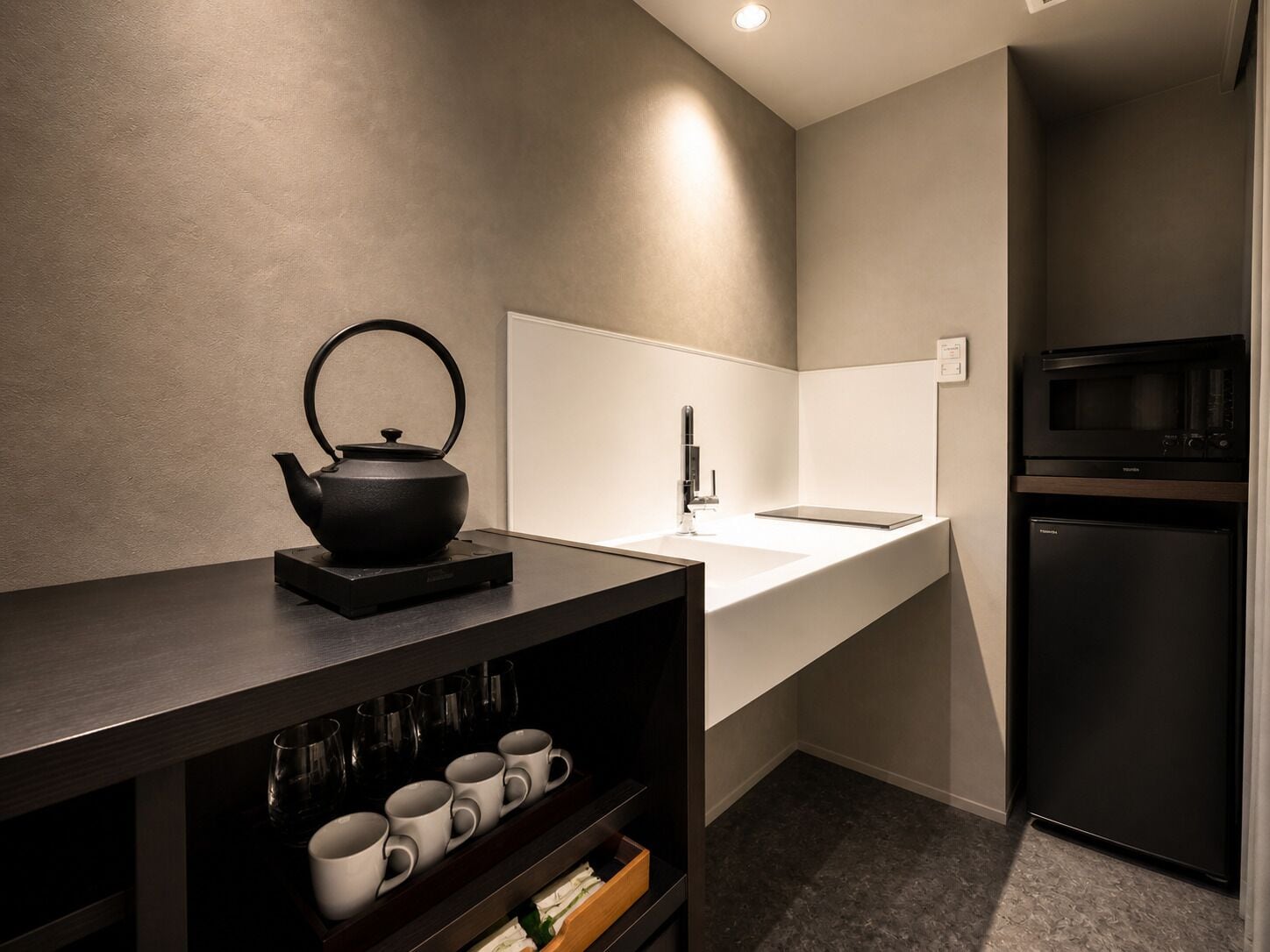 Una cocina moderna con un hervidor negro, un lavabo y un microondas.