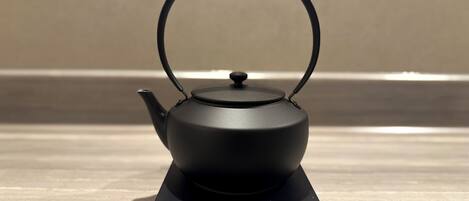 A black teapot on a stand with a label that reads 'BALMUDA.'