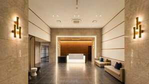 A modern lobby with a reception desk, seating area, and a restroom. - Randor Hotel Sapporo Prestige (Sapporo)