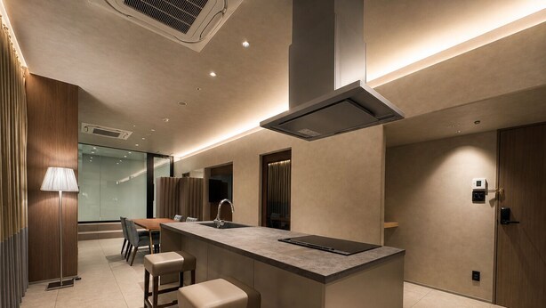 A modern kitchen with a central island, bar stools, a built-in stove, and recessed lighting. - Randor Hotel Sapporo Prestige (Sapporo)