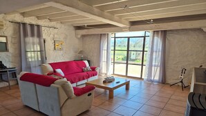 A spacious living room with a beige sofa, a red blanket, and a wooden coffee table. - Villa in Le Luc with Pool & Vineyard Views (Le Luc)