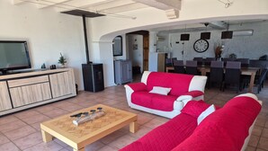 A living room with a sofa set, a coffee table, a TV, and a kitchen area visible in the background. - Villa in Le Luc with Pool & Vineyard Views (Le Luc)