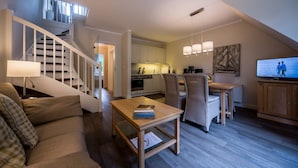 A modern living room with a staircase, a dining area, and a kitchen.