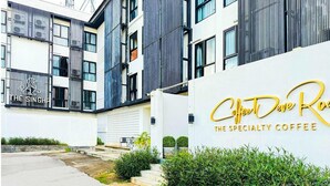 Un edificio moderno con un letrero que indica 'The Singha' y 'Coffee Dave Roo The Specialty Coffee'.
