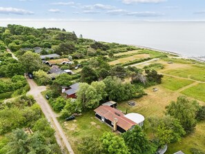 Vista aérea de una zona residencial con casas, un camino de tierra y una playa.