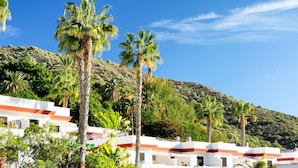 A resort with white buildings, palm trees, and a hillside in the background. - VALLE MARINA APARTAMENTOS (Arguineguin)