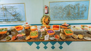 A buffet with various food items in orange bowls, a fire extinguisher, and decorative wall art. - Empire Hotel Aqua Park (Hurghada)