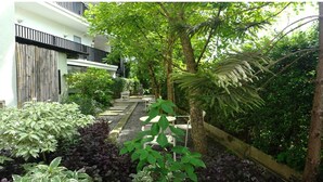 A garden pathway leading to a building with a white facade and black railings.