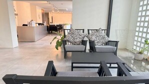 A modern living area with two grey armchairs, a black coffee table, and a potted plant. A reception desk is visible in the background.