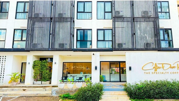 A modern building with a flat facade, large windows, and a coffee shop named "Coffee Dave The Specialty Coffee" on the ground floor.