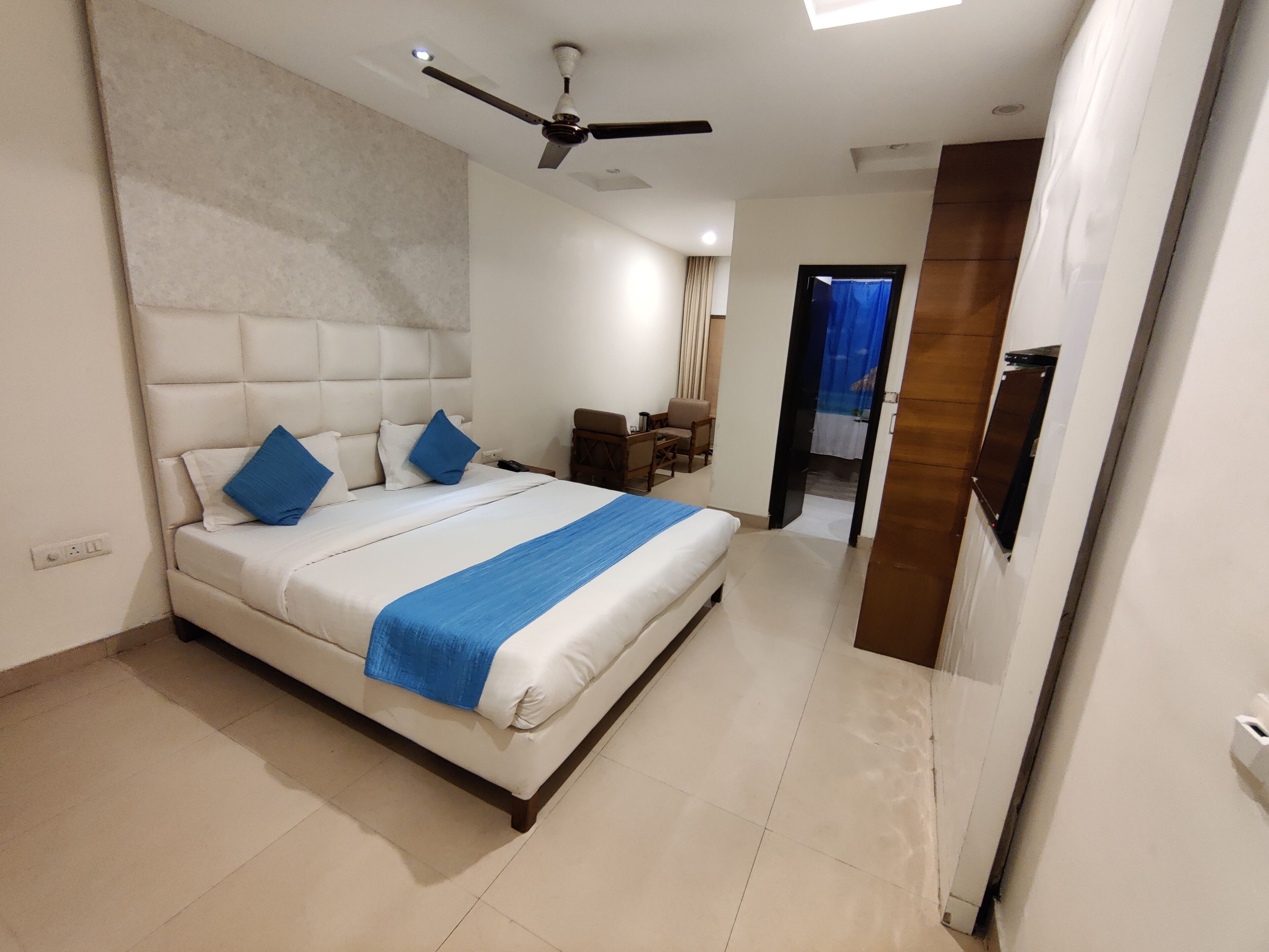 Una habitación de hotel moderna con una cama grande, un ventilador de techo y vistas al pasillo.