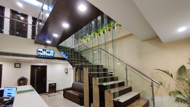 A modern interior with a staircase, a reception desk, and a flat-screen TV. - Hotel Landmark - Centre of City Chandigarh (Chandigarh)