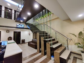 Un interior moderno con una escalera, un mostrador de recepción y un televisor de pantalla plana.
