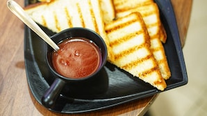 A plate of grilled sandwiches with a side of sauce and a spoon. - Hotel Landmark - Centre of City Chandigarh (Chandigarh)