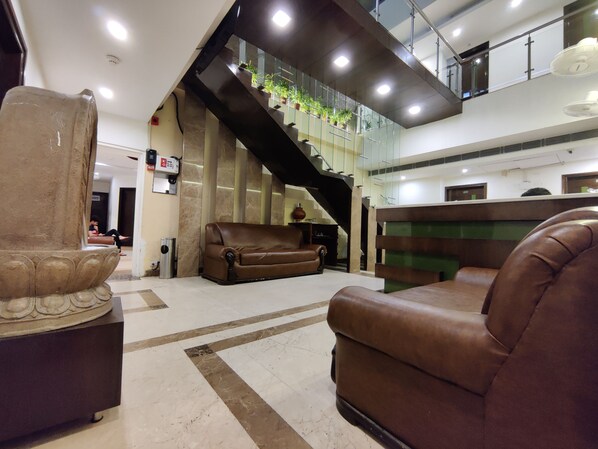 Un vestíbulo amplio con una escalera moderna, sofás de cuero y un mostrador de recepción.