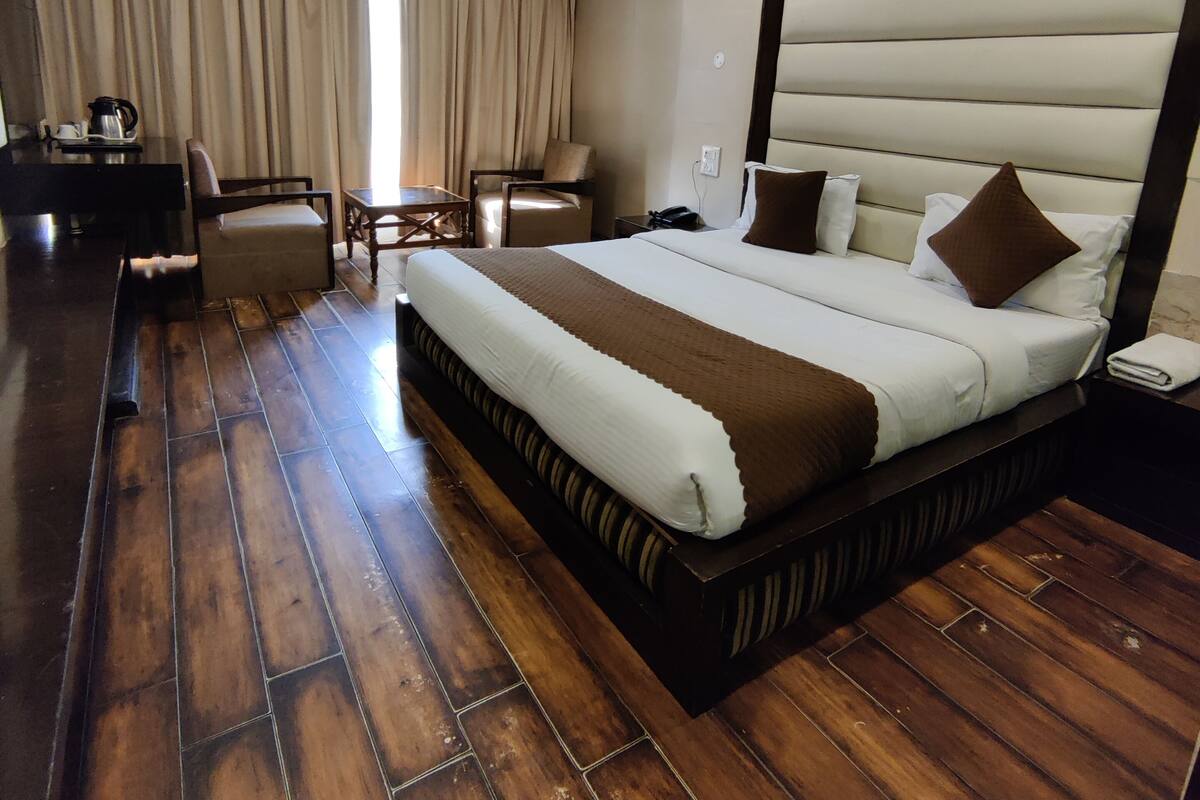 A hotel room with a large bed, a desk with a chair, a coffee maker, and a ceiling fan.