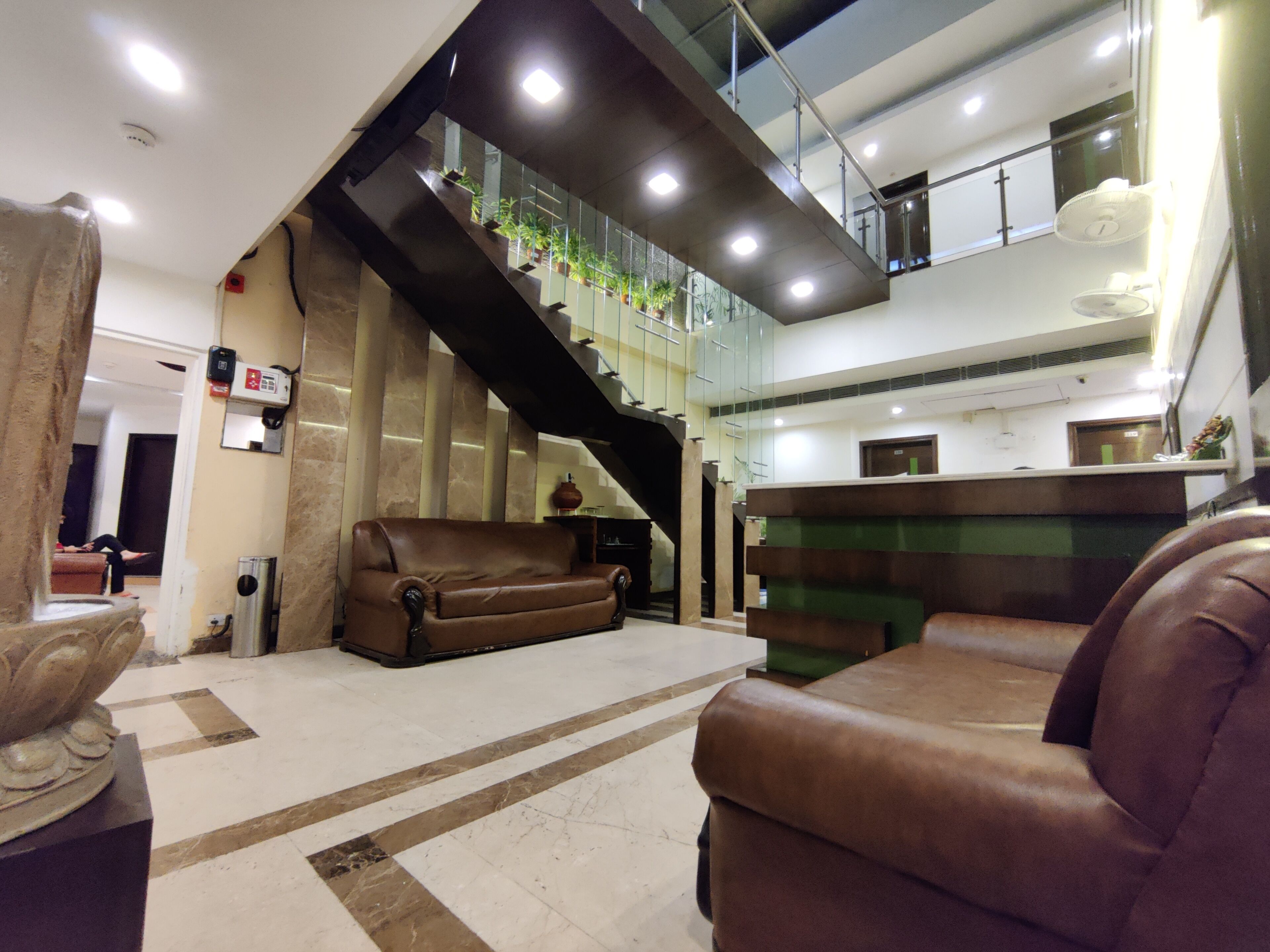 A spacious lobby with a high ceiling, a staircase, and a reception desk.