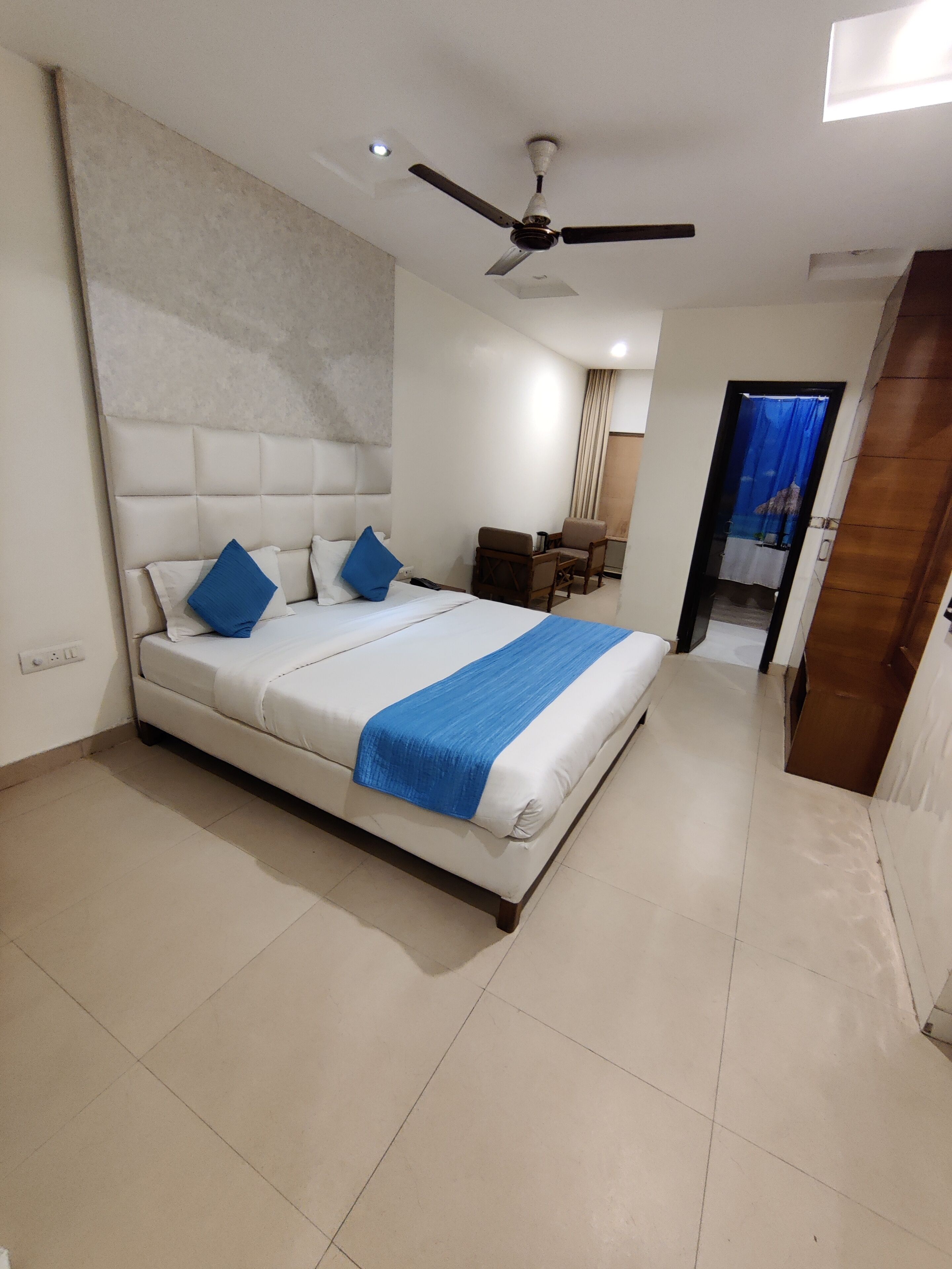 A hotel room with a large bed, a ceiling fan, a desk, and a chair.