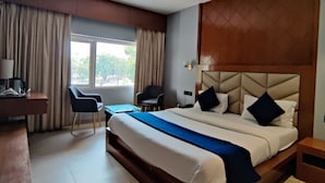 A hotel room with a large bed, a desk, a chair, and a ceiling fan. - Hotel Landmark - Centre of City Chandigarh (Chandigarh)