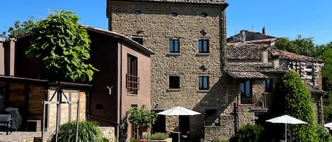 Un edificio de piedra con un patio, asientos al aire libre y una escalera que lleva a un nivel superior.