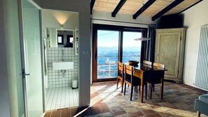 A room with a view through a large window, a wooden dining table with chairs, a white sink, and a cabinet. - Villa MOKA, modern STUDIO in a farmhouse (15th cent.);  Montefeltro (Le Marche) (Lunano)