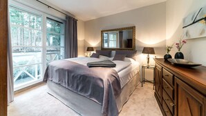 Ein Schlafzimmer mit einem großen Bett, einem Schminktisch, einem Spiegel und einem Fenster mit Vorhängen.