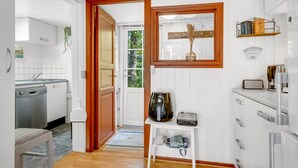 Una cocina moderna con armarios blancos, una puerta de madera y vistas al área de comedor contigua.