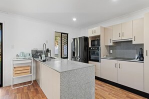 Una cocina moderna con encimera de granito, electrodomésticos de acero inoxidable y armarios de tonos claros.